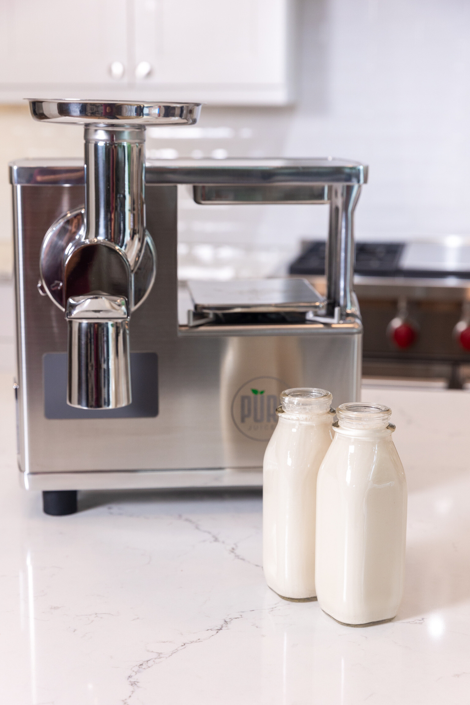 Homemade almond milk, bottled, in front of the PURE Juicer.