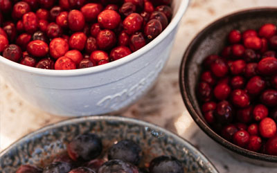 A bowl of black grapes sits in front of two bowls full of fresh cranberries.
