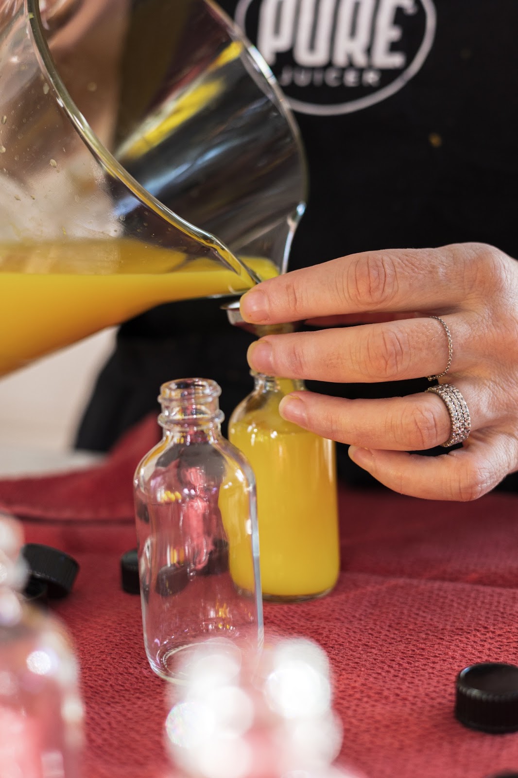 A PURE kitchen tester pours wellness shots made out of ginger, turmeric, lemons, and oranges into a small glass bottle.