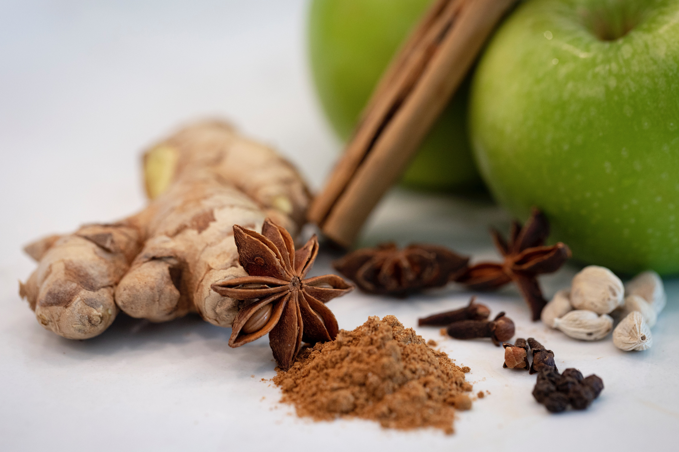 The spices we love to use in our spiced juices and mulled cider: cinnamon, cardamom, star anise, black peppercorn, and ginger, sitting next to