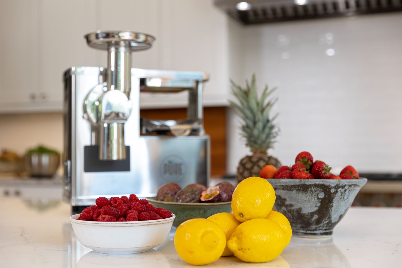 lemons and raspberries in front of pure juicer