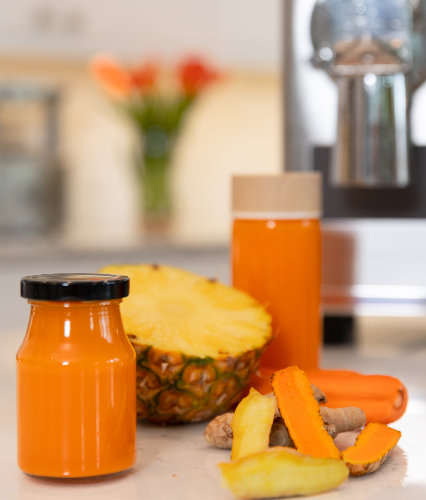 pineapple-carrot juice in jar in front of pure juicer